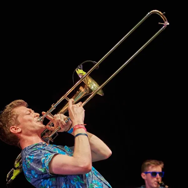 Posaunist von Duke Brass spielt vor schwarzem Bühnenhintergrund